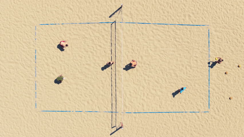 Top view of people playing volleyball on the beach of Santa Monica, Los Angeles, California, USA. Overhead shot of athletes taking part in beach volleyball competition. Healthy concept, 4k footage 