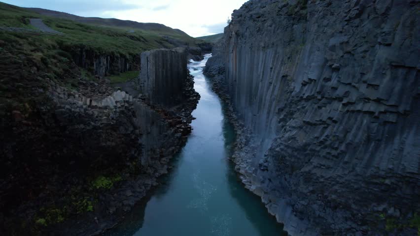 AERIAL FOOTAGE: Studlagil Canyon can be found in East Iceland in the Glacier Valley called Jokuldalur. With the largest number of basalt rock columns in Iceland and a stunning blue-green glacial river Royalty-Free Stock Footage #1107416915