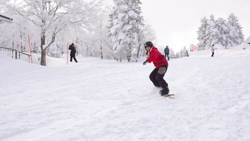 Young Asian woman practice downhill sliding snowboard on snow mountain at ski resort. Attractive girl enjoy outdoor active lifestyle travel nature and winter extreme sport training on holiday vacation