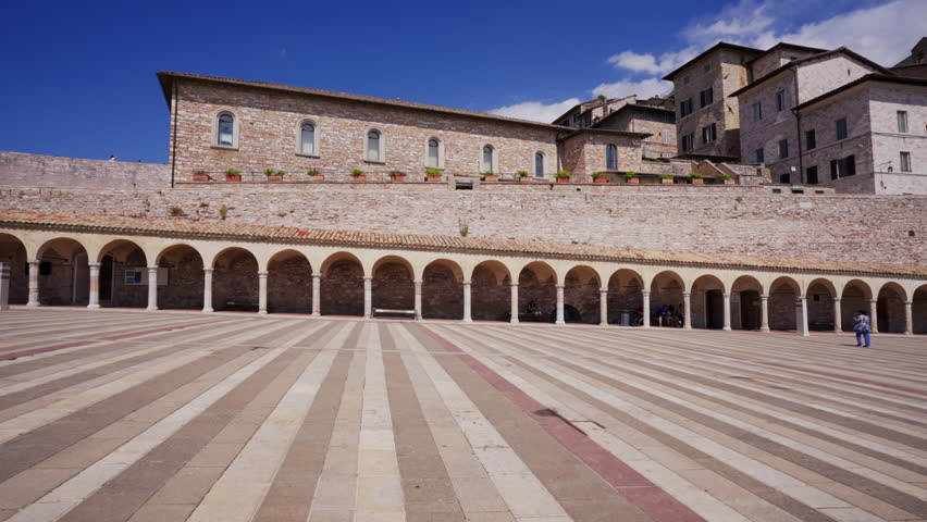 Pan of the arched walkway and lower plaza looking up to the Basilica of Saint Francis in Assisi, Italy.