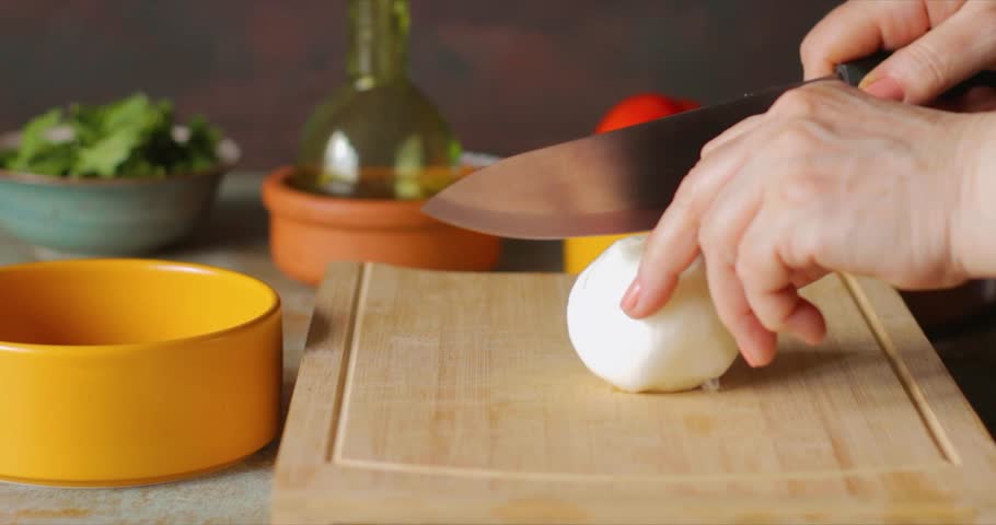 chopping onions with a large knife on a cutting board