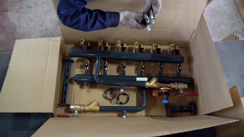 Factory Man Puts Details of Steel Plumbing Pipe into Box. Packaging process before delivery. Warehouse. Packing. Careful Manual Labor Work. Manufacture. Modern Plumbing Pipe Production Plant. Top View