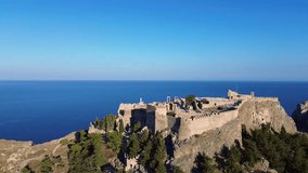 Acropolis of Lindos in Rhodes, Greece with houses and Mediterranean sea during the day filmed with the drone