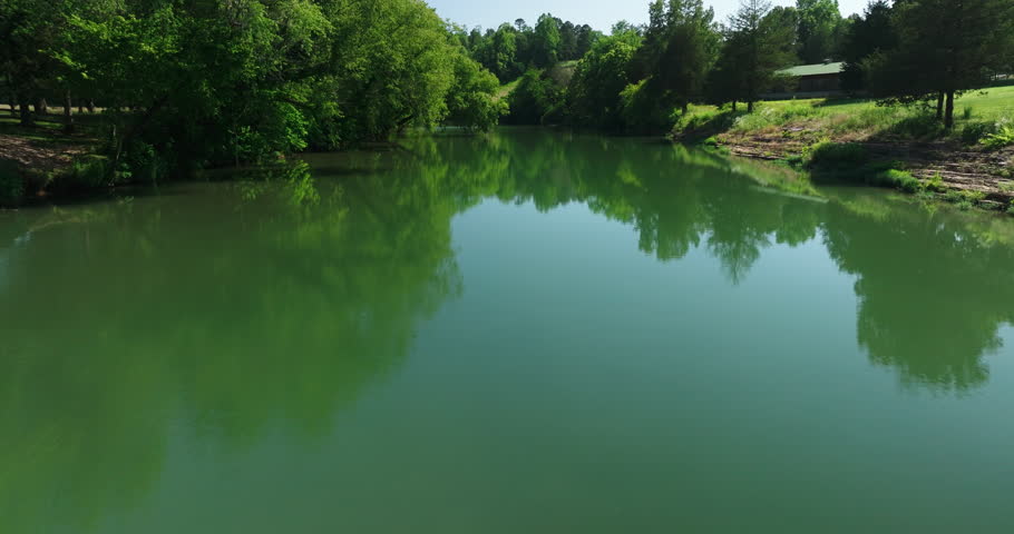 Aerial flyover of mirror-like creek, lush forest scenery. Ozarks, Arkansas