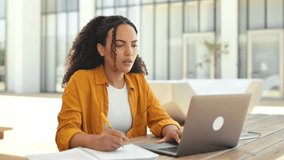 Tired brazilian or hispanic curly young woman, freelancer, university student, sitting outdoors, near campus, with laptop, looks puzzled to the side, feels overworked, experiencing headache, migraine - Powered by Shutterstock - Get 15% off with code: PIKWIZARD15