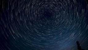 Time lapse of comet-shaped star trails over the forest in the night sky. Stars move around a polar star. Ultra 4K - Powered by Shutterstock - Get 15% off with code: PIKWIZARD15