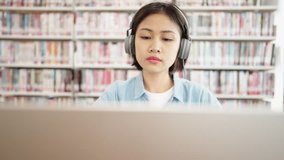 Asian female students university wear headphones and learn online on laptop computer in library,Studying for Exams College Book in library - Powered by Shutterstock - Get 15% off with code: PIKWIZARD15