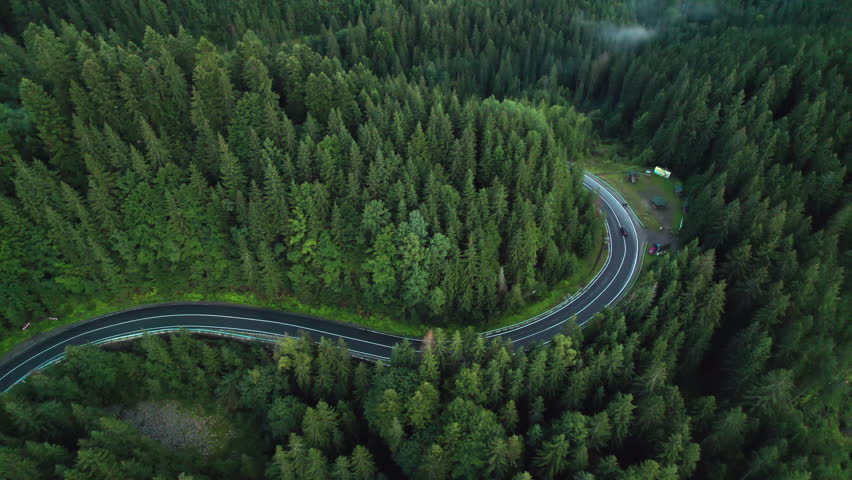 Aerial bird's eye view flying over winding road in forested mountains Royalty-Free Stock Footage #1107444815