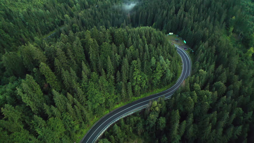 Aerial bird's eye view flying over winding road in forested mountains Royalty-Free Stock Footage #1107444817