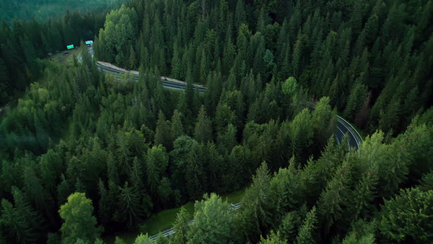 Aerial bird's eye view flying over winding road in forested mountains Royalty-Free Stock Footage #1107444923