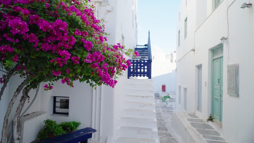 Walking in picturesque scenic narrow streets with traditional whitewashed houses with blue doors windows of Mykonos town in famous tourist attraction Mykonos island, Greece
