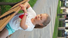 A girl in the park is talking on her watch. Smart watches are an alternative to a smartphone. Parents control the child. Have a video call on your smartphone. Children's wristwatch with a GPS tracker