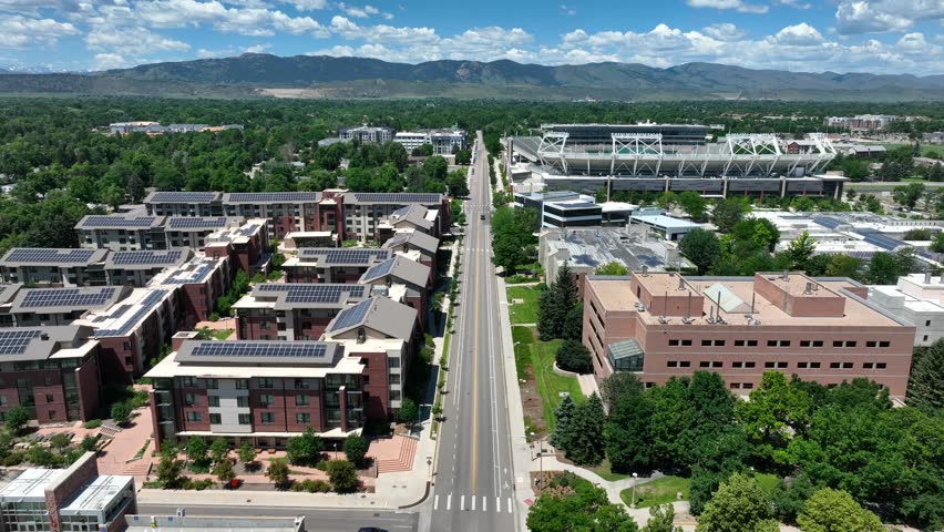 College campus dorms and apartments with solar panels on roofs with university stadium. Aerial shot of Colorado State University in Fort Collins with a mountain backdrop in summer. Royalty-Free Stock Footage #1107451655