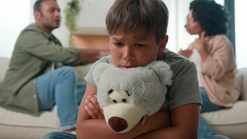 Multiracial family quarrel mother and father scream in anger argue at home sad scared little boy hug teddy bear toy domestic violence trauma upset son child suffer from parents conflict on background Royalty-Free Stock Footage #1107454489