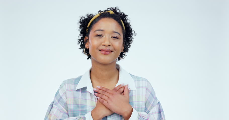 Woman, face and thank you with hand on chest in studio for grateful, gesture or sign against white background. Portrait, smile and female model with emoji on heart for gratitude, peace and self love Royalty-Free Stock Footage #1107463195