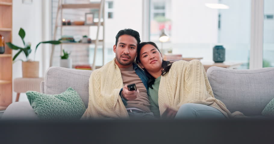 Watching tv, movies and a couple on a home sofa with a remote control for choice and relax. Asian man and a woman together on a couch for streaming subscription, show or series with comfort and care