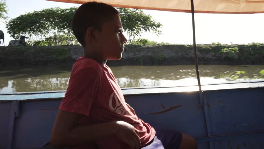 A young black man gazes at the stunning panorama of the Magdalena River in Mompox, Colombia, as the afternoon sun bathes the scene in warm hues. Sitting on a fishing boat, you are immersed in the natu