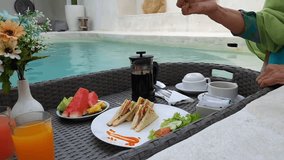 Picking sandwich floating breakfast poolside at a tropical luxury villa during vacation - Powered by Shutterstock - Get 15% off with code: PIKWIZARD15