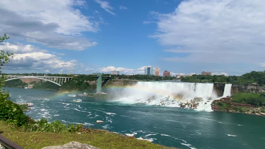 Looking at the American Falls from the Canadian side as the Maide of the mist boat rides through a full rainbow and seagulls flying.