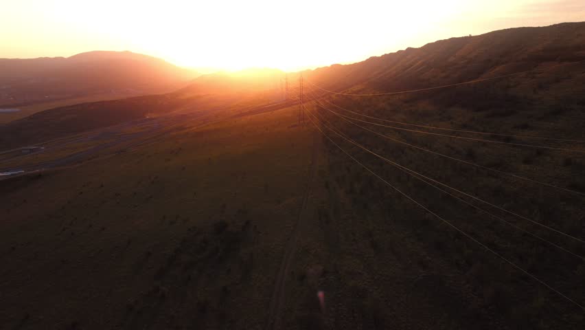 Beautiful hills and mountains at sunset. Rays of the sun, power lines, energy supply.