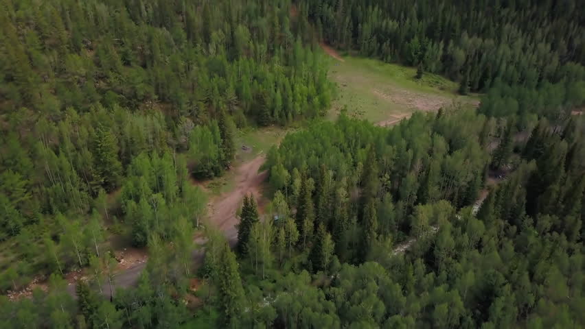 Aerial Tilt Down Shot Of Car On Dirt Road Amidst Green Trees Near River In Forest - Colorado Springs, Colorado