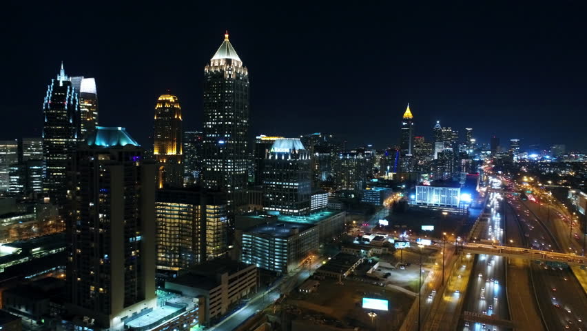 Aerial Panning Shot Of Buildings Amidst Streets In Illuminated City, Drone Flying Over Modern Structures At Night - Atlanta, Georgia