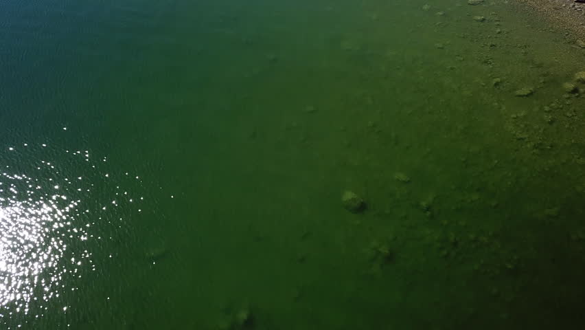 Aerial Tilt Up Shot Of Lake With People At Hill Against Sky On Sunny Day, Drone Flying Over Lakeshore Near Mountain Ranges - Billings, Montana