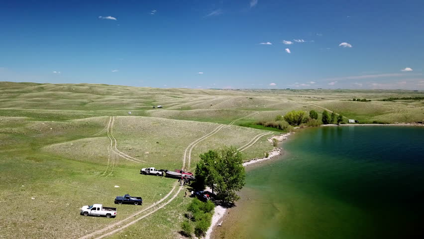 Aerial Panning Shot Of Vehicles And People At Lakeshore Against Blue Sky, Drone Flying Over Lake - Billings, Montana