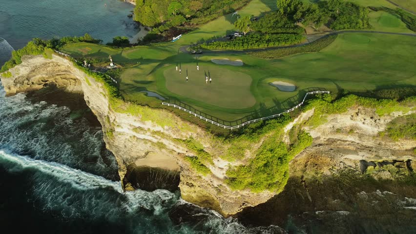 Drone footage of a group of people playing golf at a country club perched on a cliff by the ocean. Green golf course on the coast, people play golf. Royalty-Free Stock Footage #1107492141