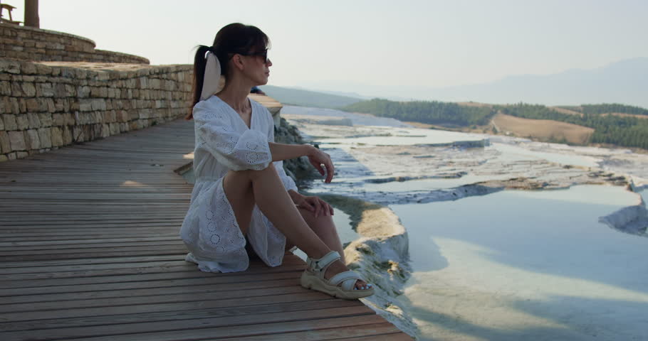 Young woman sitting and looking on Pamukkale terraces travertine pools, Turkey discovery
