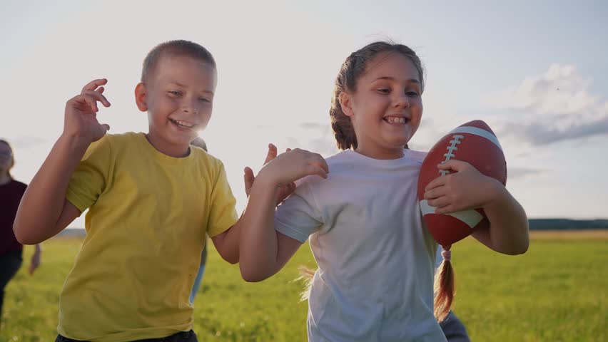 children playing rugby in the park. group of children play american football run outdoors in the park in summer. happy family lifestyle kid dream concept. family children play american football run