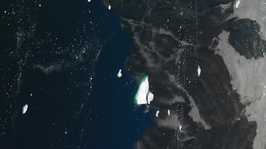 Vertical video reflection of snowy mountain in water of Antarctic Ocean. Unique allure of Antarctic Ocean is attributed to combination of snowy mountains, ice and icebergs. Aerial view of Antarctica.