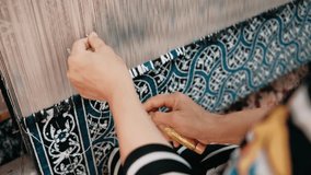 Woman weaving traditional Asian carpet. Handmade carpet embroidery. Women hands create a pattern using multi-colored threads. Weaving machine. Needlework. Carpet-makers. - Powered by Shutterstock - Get 15% off with code: PIKWIZARD15