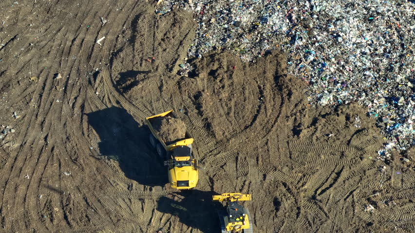 Aerial view of big landfill dumping site with bulldozer tractors burying large amount of trash under the ground. Harmful impact of modern consumerism on environment Royalty-Free Stock Footage #1107496565