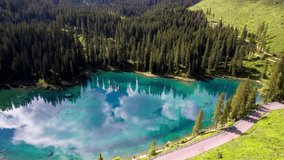 Idyllic nature scenery- trasparent mountain lake Carezza surrounded by Dolomites rocks- one of the most beautiful lakes of Alps. South Tyrol region. Italy, aerial drone video