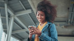 Happy young African American woman using mobile phone with chatting online with friends, Female in jean jacket sitting in the city using social media on smartphone, Technology - Powered by Shutterstock - Get 15% off with code: PIKWIZARD15