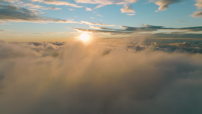 Flight above the clouds towards the sun. Misty weather, view from above. Birds point of view. Aerial camera shot.