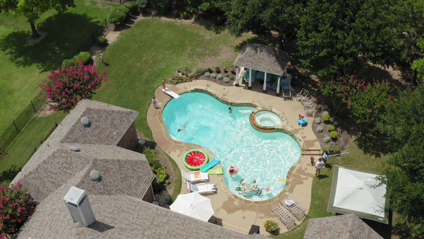Aerial view of backyard swimming pool party on bright summer afternoon, Texas