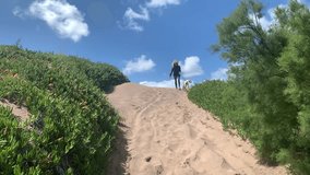 Woman and dog having fun while walking down a sand dune.