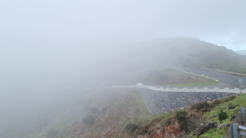 Thick fog at the top of the mountain. Mountain road. Danger