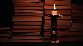 Candle in candlestick with old books, slider footage in antique shop, bookstore.
