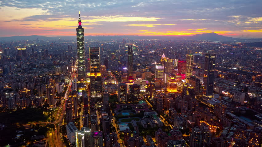 Aerial hyperlapse at sunset above Downtown Taipei, the vibrant capital of Taiwan, with 101 Tower standing out amid skyscrapers in XinYi Commercial District and city lights dazzling under twilight sky