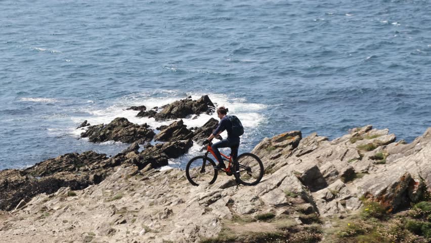 Newquay , United Kingdom (UK) - 08 15 2023: tracking shot of a man mountain biking at the Towan Headlands in Newquay