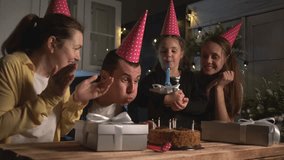 father blows out candles. family celebrating birthday. cake with candles. father blows out candles on birthday cake. Happy family at table in decorated kitchen during birthday celebration - Powered by Shutterstock - Get 15% off with code: PIKWIZARD15