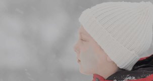 Boy catches snowflakes with his mouth open and his tongue. Child in winter during the snow. Side view