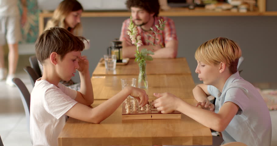 Two children playing chess in cafe. Chess is a strategic game that stimulates critical thinking, problem-solving, and cognitive skills. Kids mentally stimulating indoor activity. People lifestyle. Royalty-Free Stock Footage #1107518685