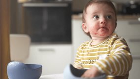 grimy baby eats with her hands from a plate. development of fine motor skills family kid dream concept. funny video baby dirty eats food from a plate with his hands lifestyle. dirty baby eats