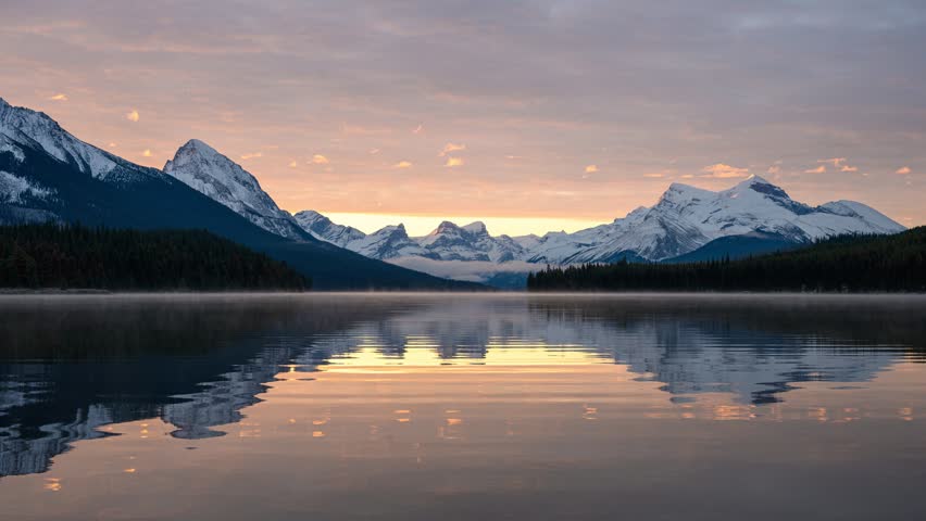 Time lapse beautiful scenery of sunrise over mountain range and water reflection in Maligne Lake at Jasper national park, Alberta, Canada