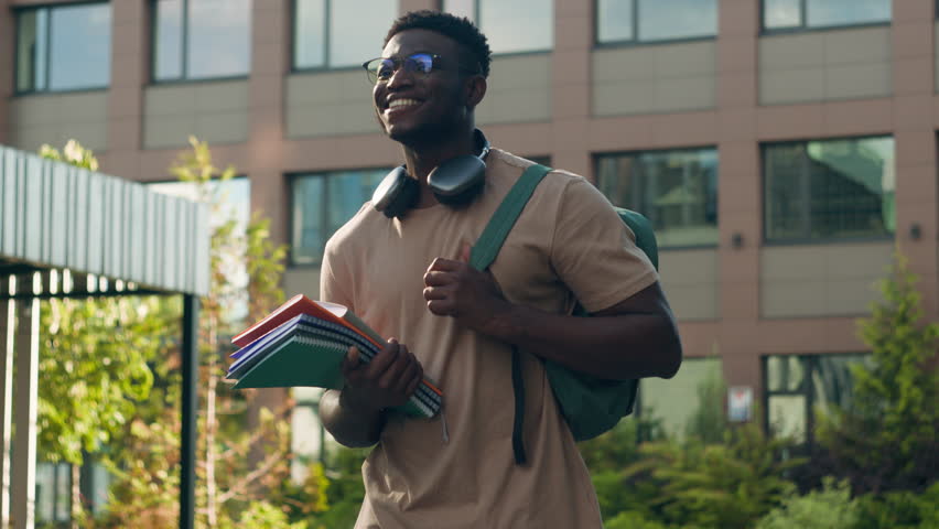 African American happy smiling student guy ethnic university man male with backpack school bag and books smile walking in city outdoors in academy college university campus on education class lesson Royalty-Free Stock Footage #1107529653
