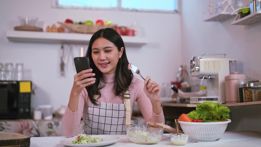 Beautiful Asian woman using an application to send a instant message in her smartphone device while eating spaghetti